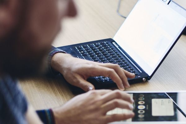 Person sitting at a table with a laptop and tablet